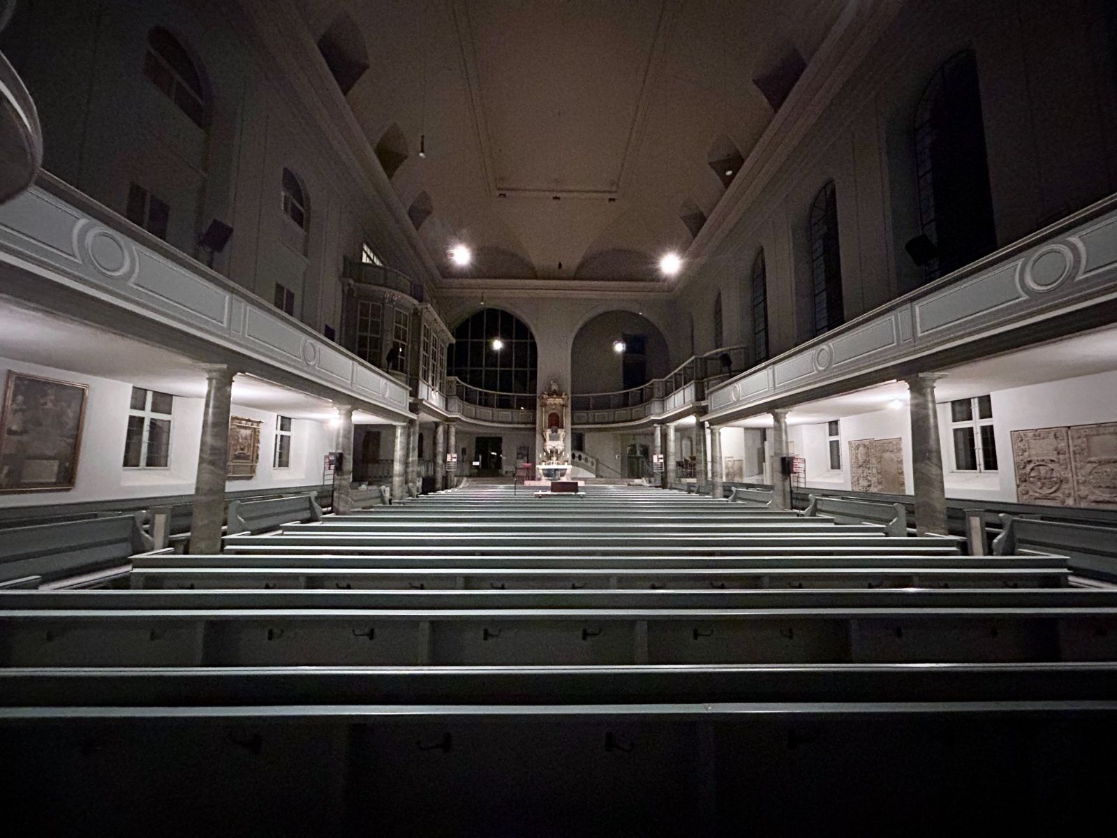 Der leere Kirchenraum am Abend, Blick über die Bänke zum Altar